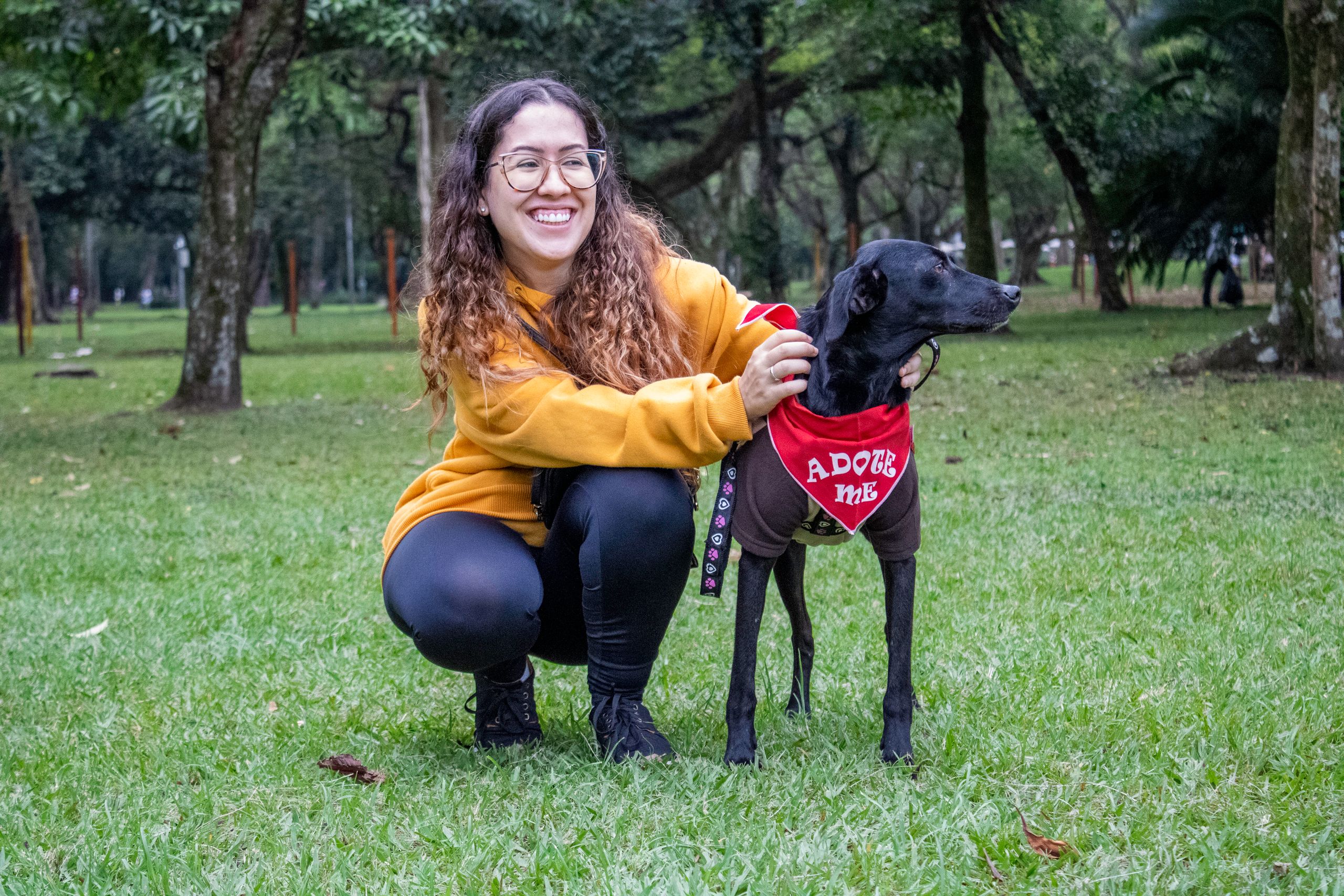 Lächelnde Frau mit schwarzem Mischlingshund aus dem Tierschutz im Park